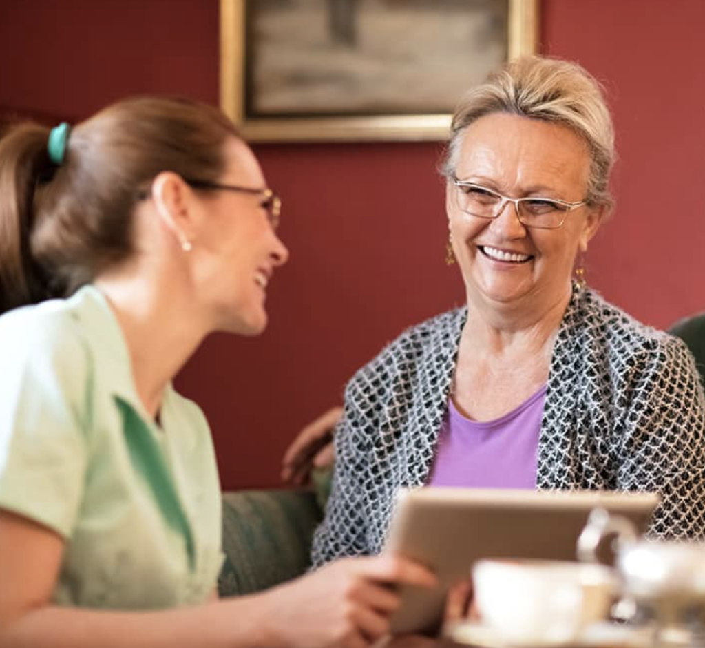 Two middle-aged people sitting indoors, smiling and laughing with each other